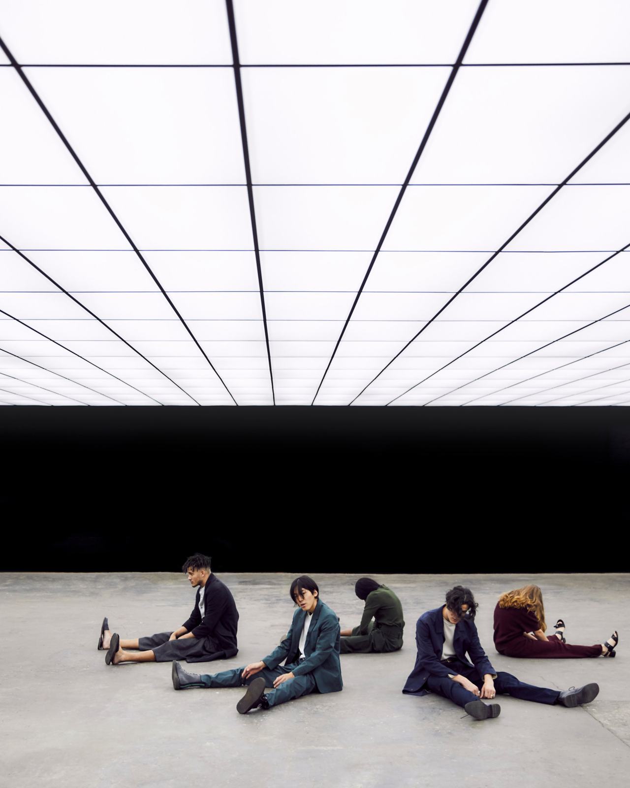 A team sitting together on the floor of a large white studio